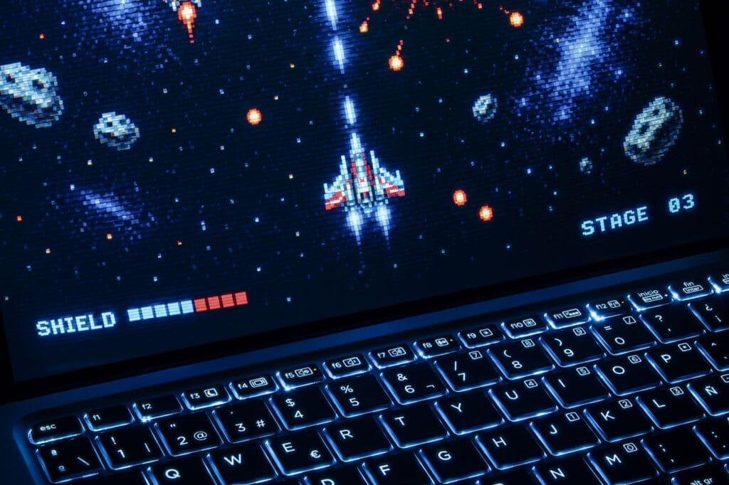 Laptop z retro strzelanką kosmiczną w stylu pixel art