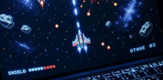 Laptop z retro strzelanką kosmiczną w stylu pixel art