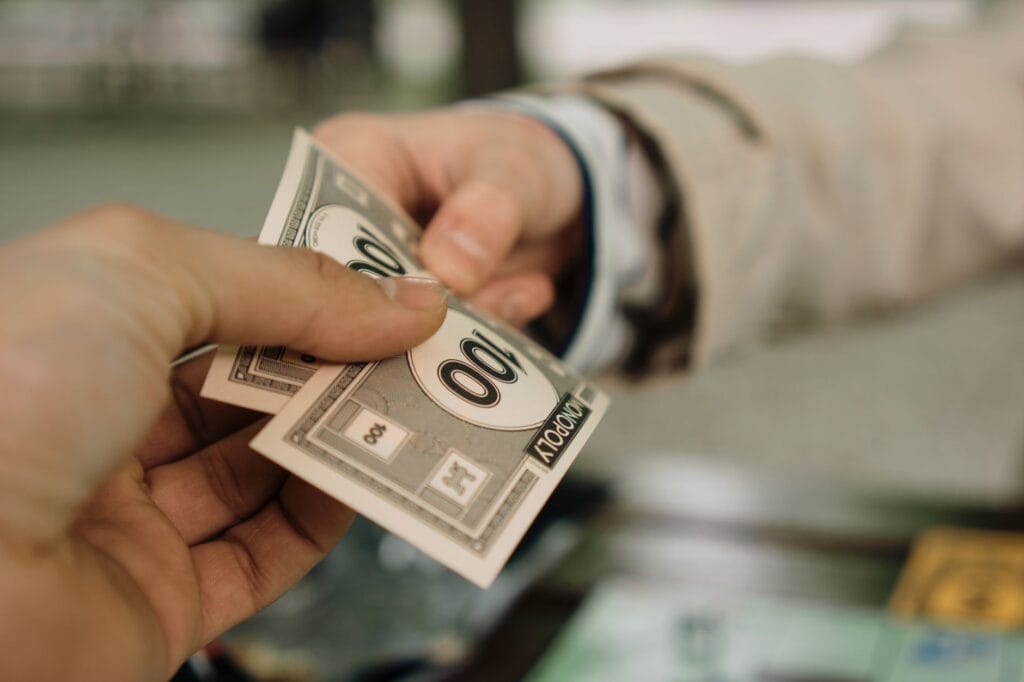 Zbliżenie na dłonie wymieniające banknoty Monopoly jako transakcję finansową