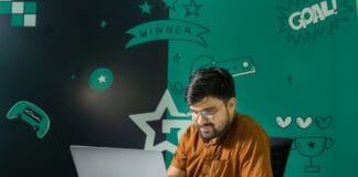 Kariera w QA i testowaniu gier: czy to dobry punkt wejścia do branży gamedev Mężczyzna z brodą gra na laptopie w domu udekorowanym grafikami z gier
