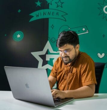 Kariera w QA i testowaniu gier: czy to dobry punkt wejścia do branży gamedev Mężczyzna z brodą gra na laptopie w domu udekorowanym grafikami z gier
