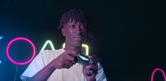 Skupiony młody gracz przy komputerze w neonowym świetle