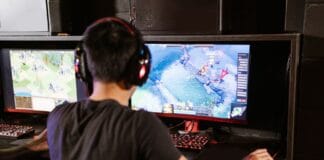 Frame pacing w grach: dlaczego stabilne 60 FPS nadal może wyglądać na zacinanie? Gracz przy komputerze z dwoma monitorami i słuchawkami